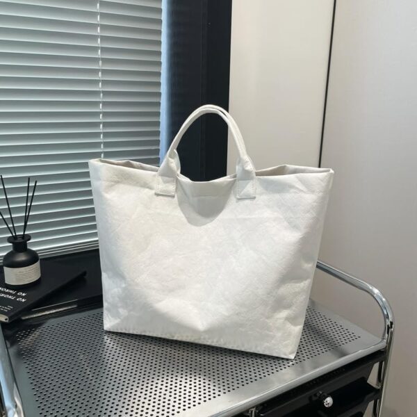 White DuPont Paper Tote Bag Manufacturer Guide: MOQ 500, 20–25 Days Lead Time & Global Delivery for Bulk Travel Bag Orders 2 white tote bag placed on a reflective glass table, thumbnail preview with the numeric code 4-8-18-6.