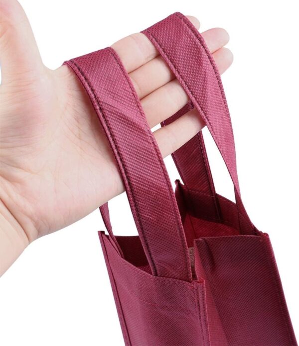 Non-Woven Wine Gift Bags for Retail & Event Gifting: GSM & Custom Print Options | Xiangfu Wholesale Sourcing Guide 3 Close-up of a hand holding a dark red non-woven wine bag, showing durable handle construction for heavy bottles.